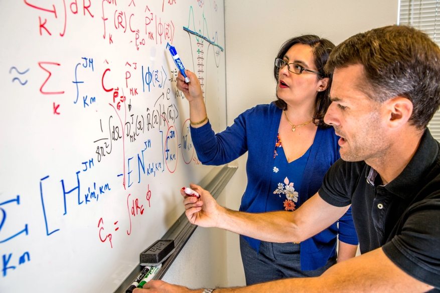 Researchers write formulas on a whiteboard